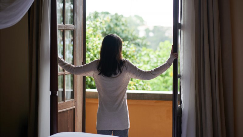 A woman opening a window (Photo by DragonImages/iStock/Getty Images Plus via Getty Images)