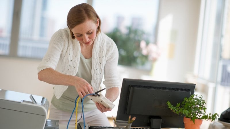 A woman plugging ethernet cable to the router (Photo by Tetra Images via Getty Images)