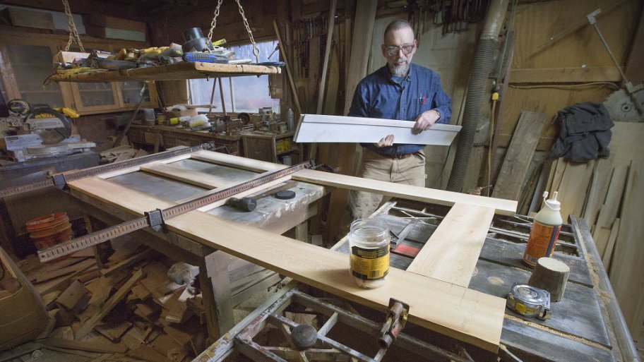 Kerry Barnard, The Front Gate's restoration carpenter, examines the panels of a wooden antique door.