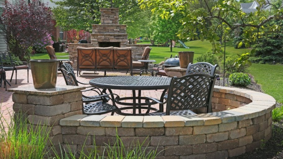 Back yard with stone patio, chairs and fireplace