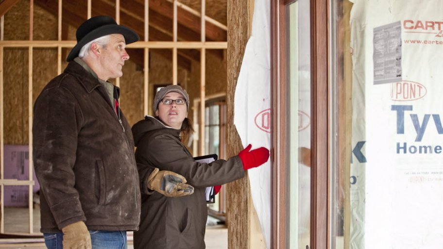 A male homeowner and female LEED verifier look at the inside of a home under construction