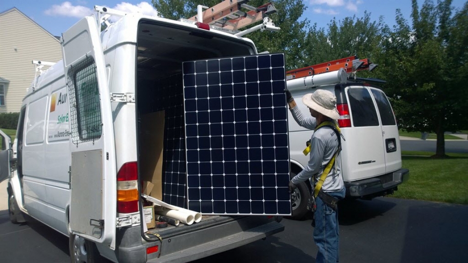 a solar panel installer pulling some out of a van