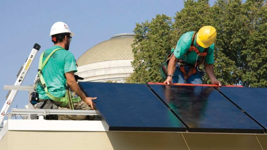 Two men installing solar panels on a rooftop