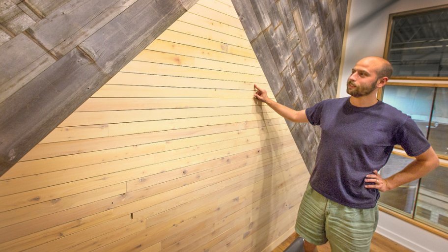 Tri-Lox co-founder Ellis Isenberge looks at a interior wall made from reclaimed wood