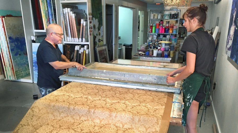 Walter Knabe and assistant Emily McAvoy screen print a roll of gold custom wallpaper
