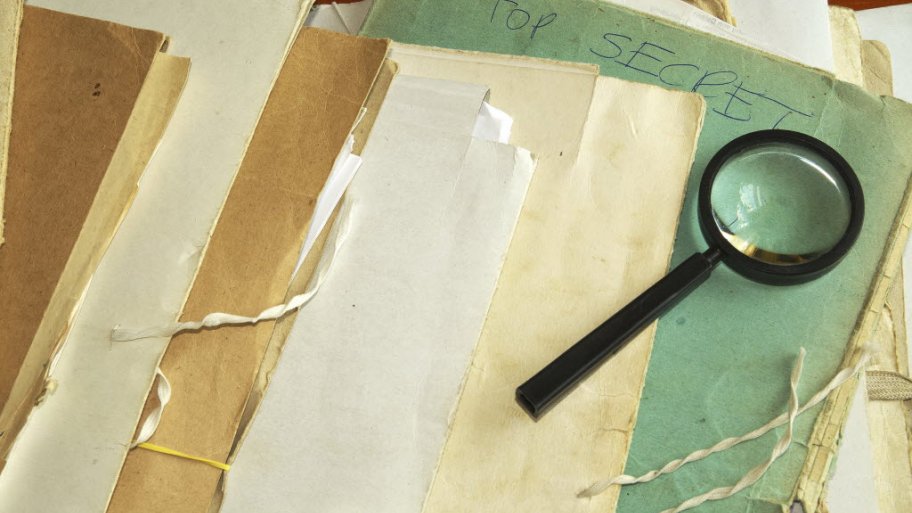 a magnifying glass on top of some old files and folders