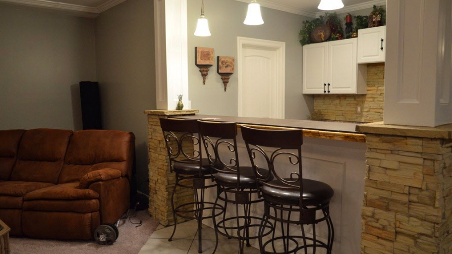 remodeled basement with bar, cabinets and seating area