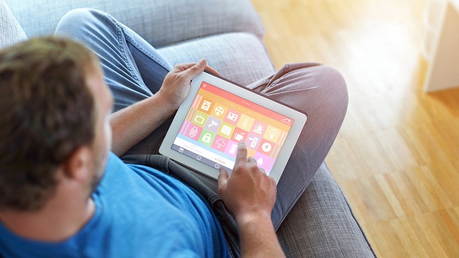 man sitting on couch tapping electronic device