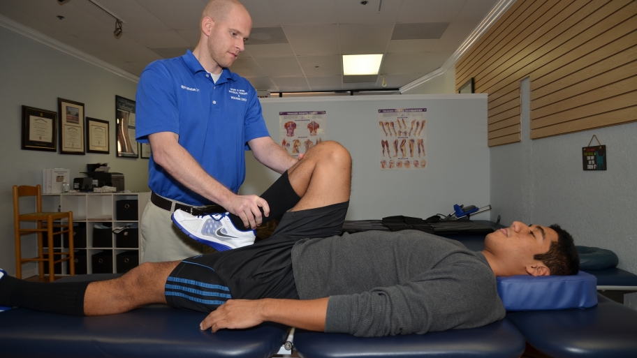 physical therapist assisting man's exercise
