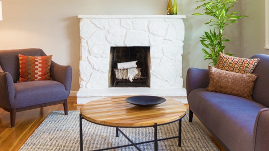 painted white stone fireplace flanked by chair and sofa