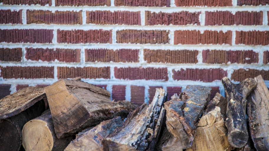 firewood stacked next to a brick wall