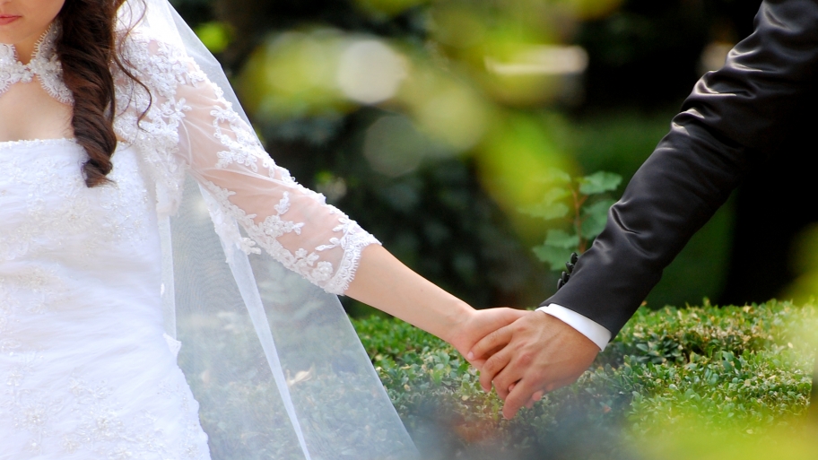 bride holding groom's hand outside