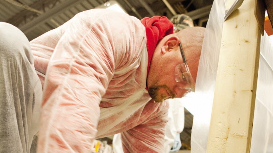 A man creates a plastic barrier for a lead-contaminated worksite.