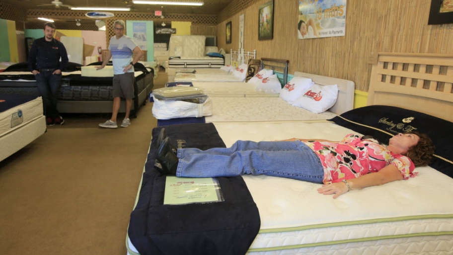 two people shopping for a mattress with a salesman