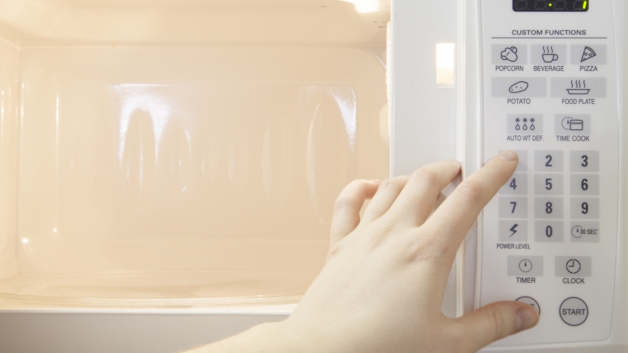 hand pushing buttons on a microwave oven