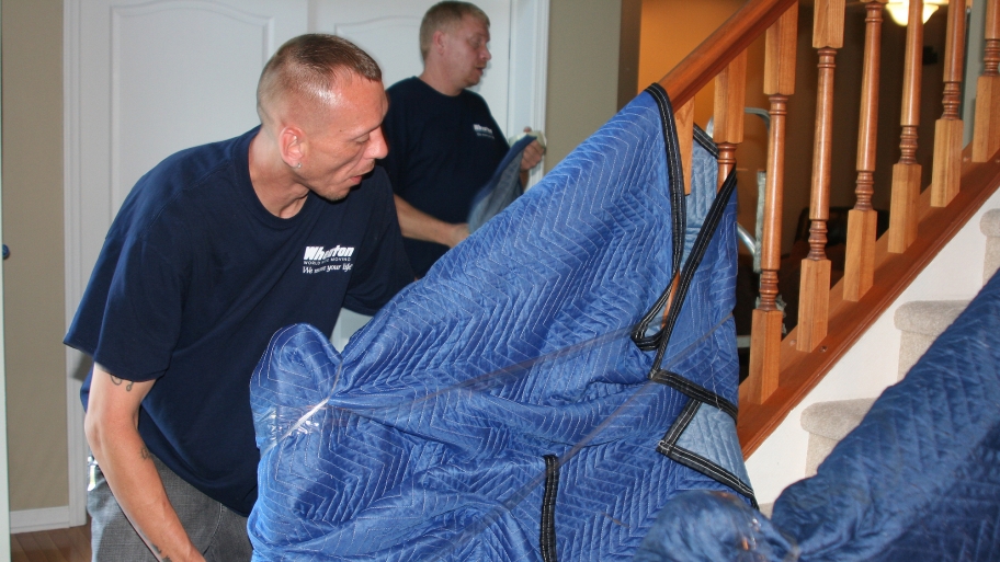 movers protecting stair banister with moving blanket