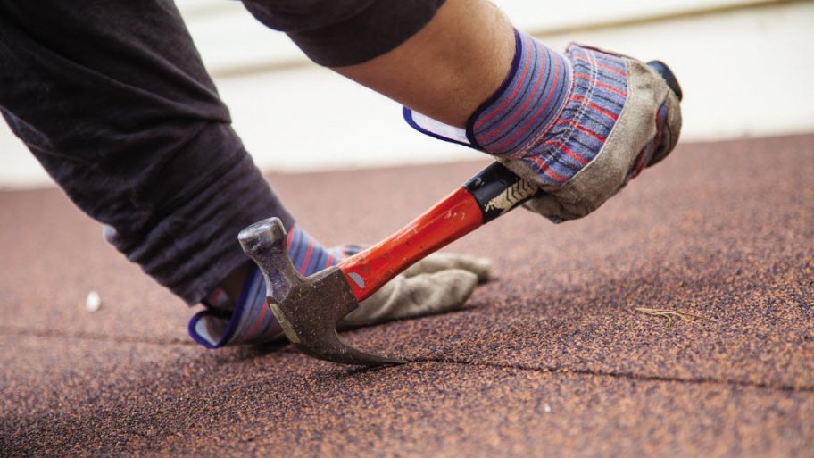 A man works on a roof with a hammer