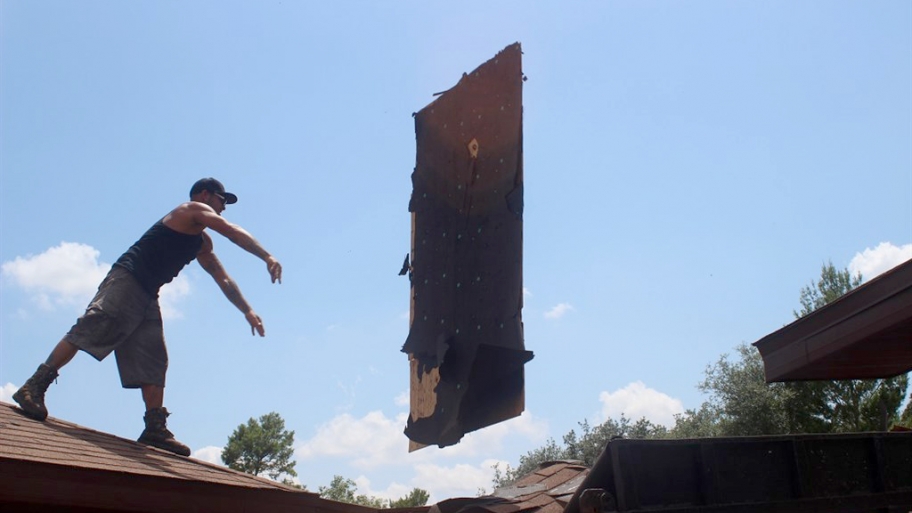 roofer throwing damaged plywood from a roof