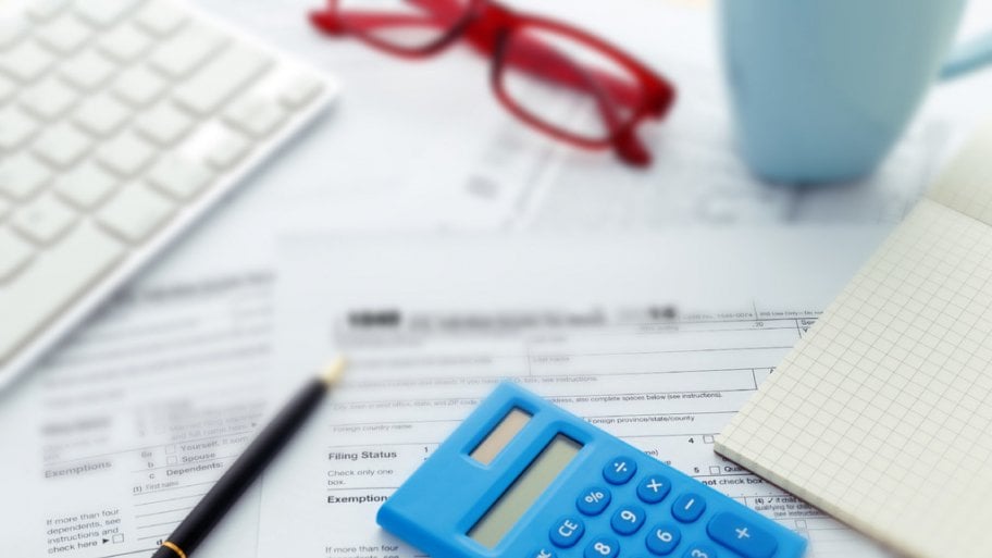 calculator and pen with some tax forms