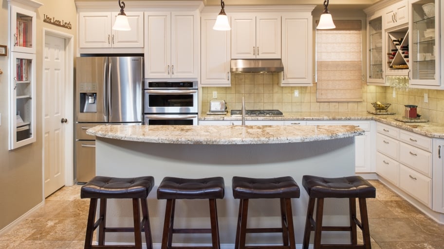 transitional kitchen with quartz countertops, curved kitchen island, steel appliances and contemporary stools
