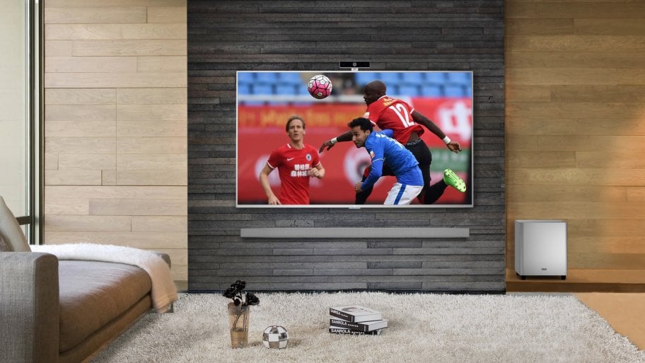 Lifestyle shot of a LeEco 4K Ultra HD TV showing a soccer game, wall mounted in a living room.