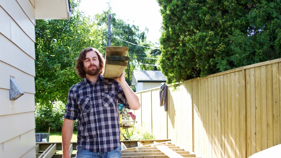 construction worker carrying deck boards