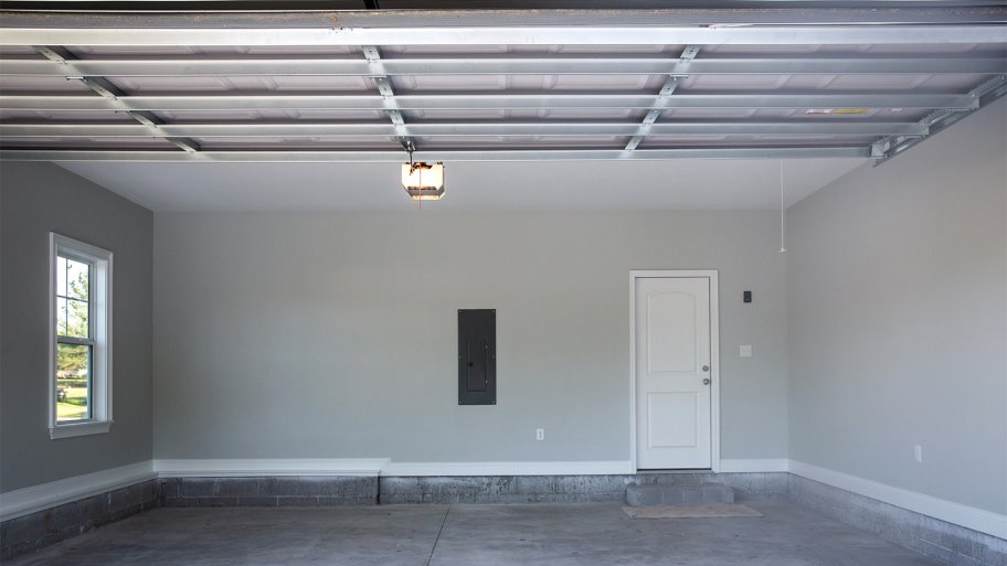 Empty two car garage with door leading inside home