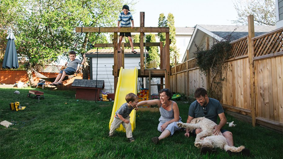 Family playing on a backyard playground and swing set