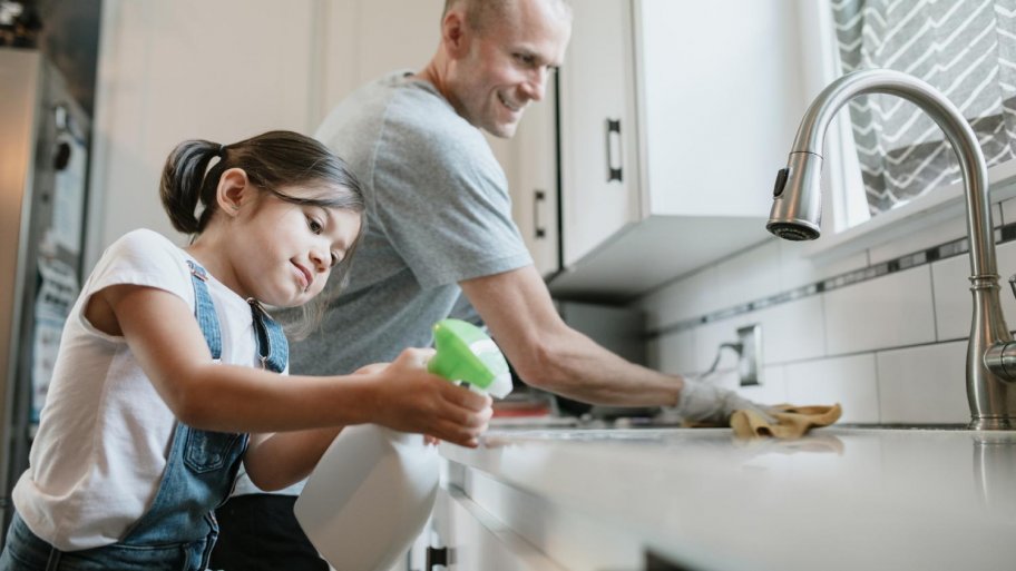 A father and his daughter cleaning their kitchen sink