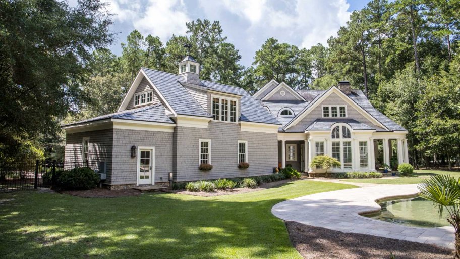 A large gray house with wood shingle and a chimne