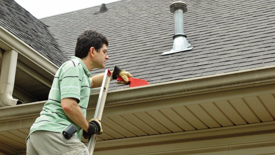 man on ladder cleaning gutter