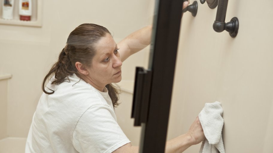 housekeeping company employee cleanign a shower