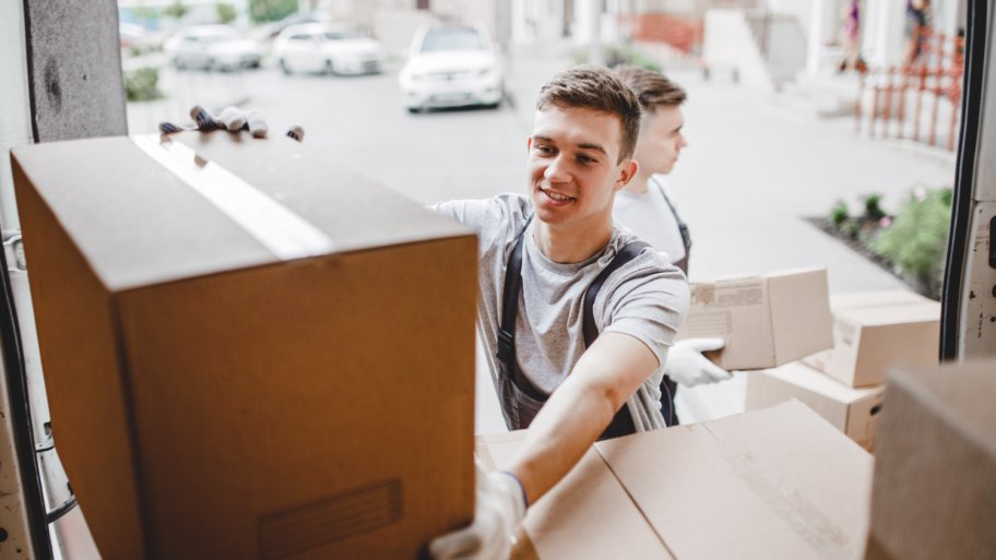 A mover reaching for the box while unloading the van full of boxes (Photo by Leika production - stock.adobe.com)