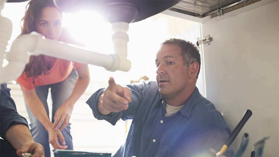 Plumber showing homeowner kitchen sink pipes