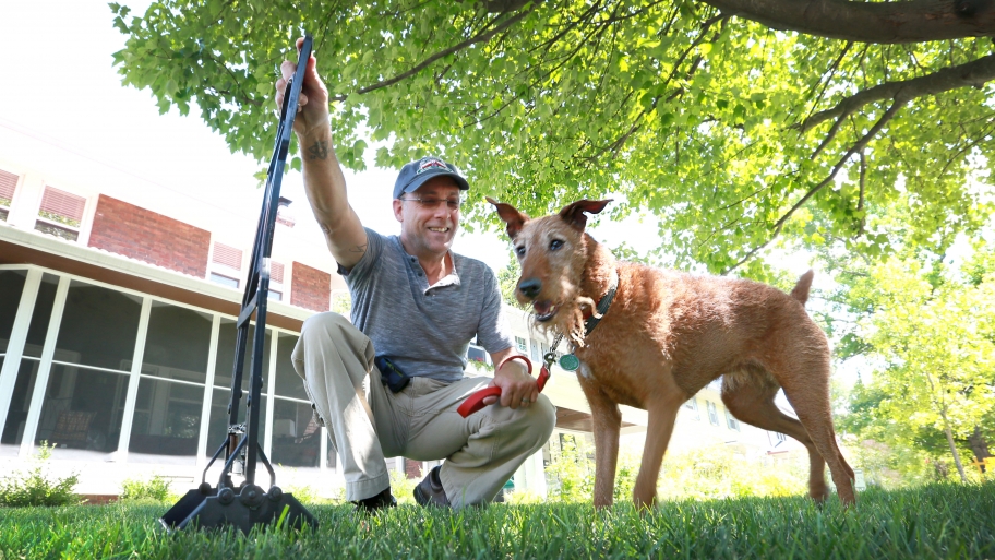 man with pooper scooper and dog
