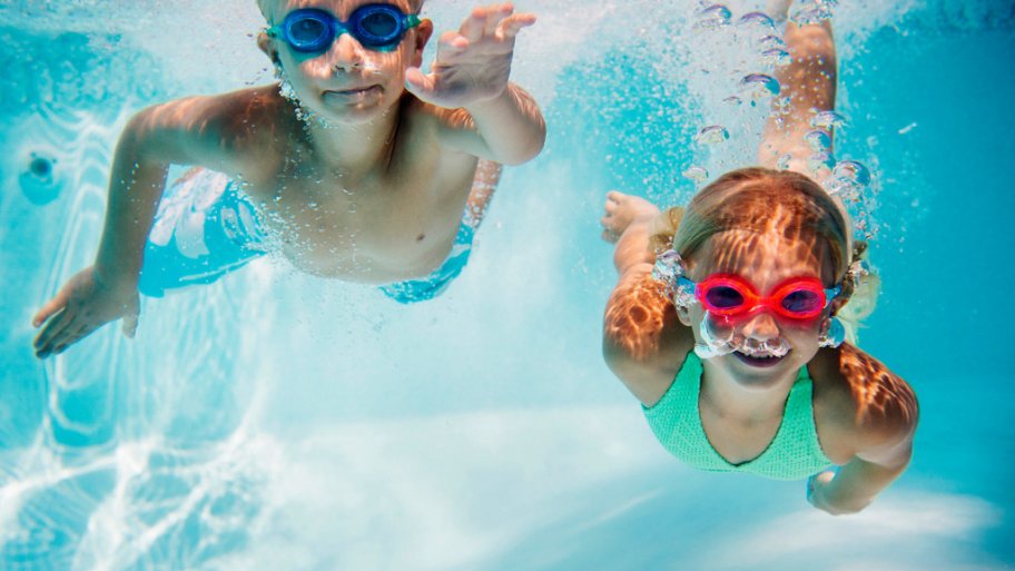 Two kids swimming underwater with goggles