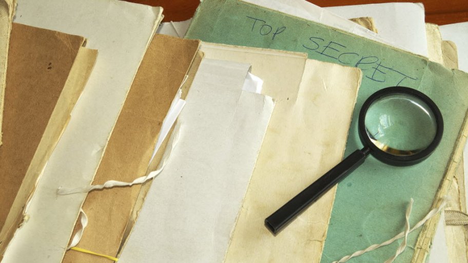 a magnifying glass on top of some old files and folders