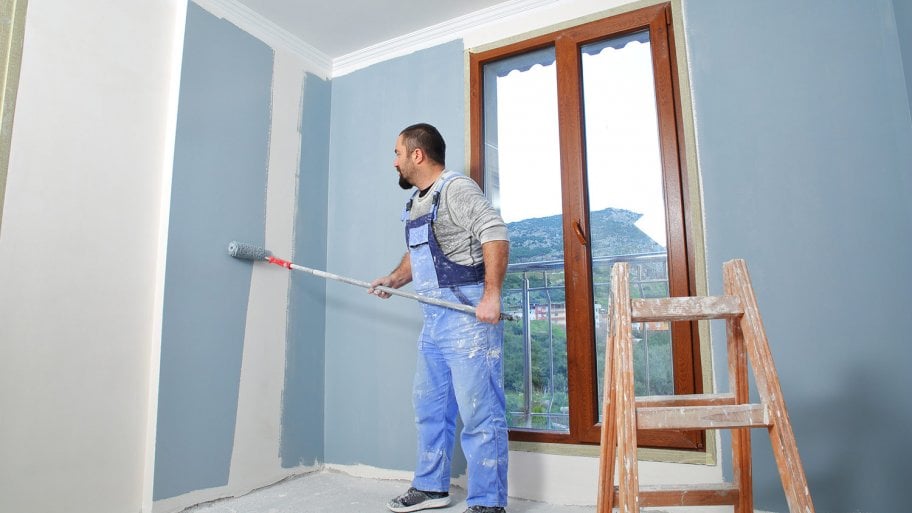 Painter at work painting room blue