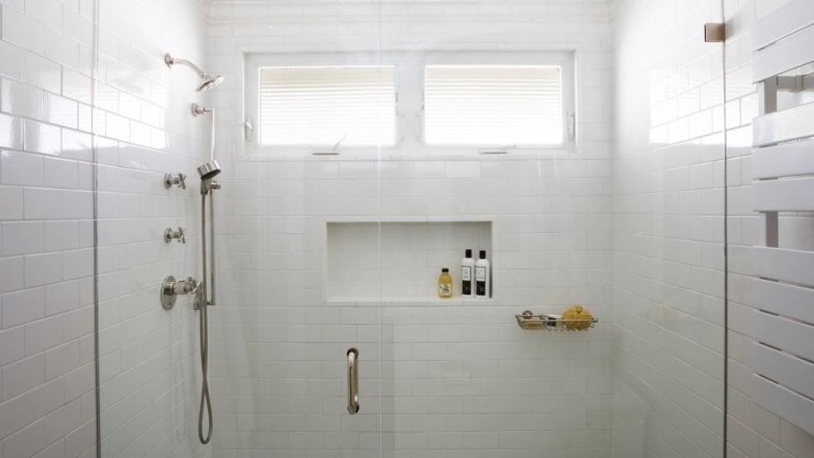 A bright white tiled bathroom with a shower