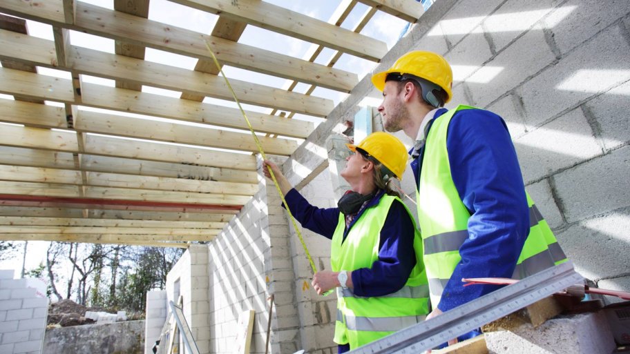 Two builders taking measurements in construction site