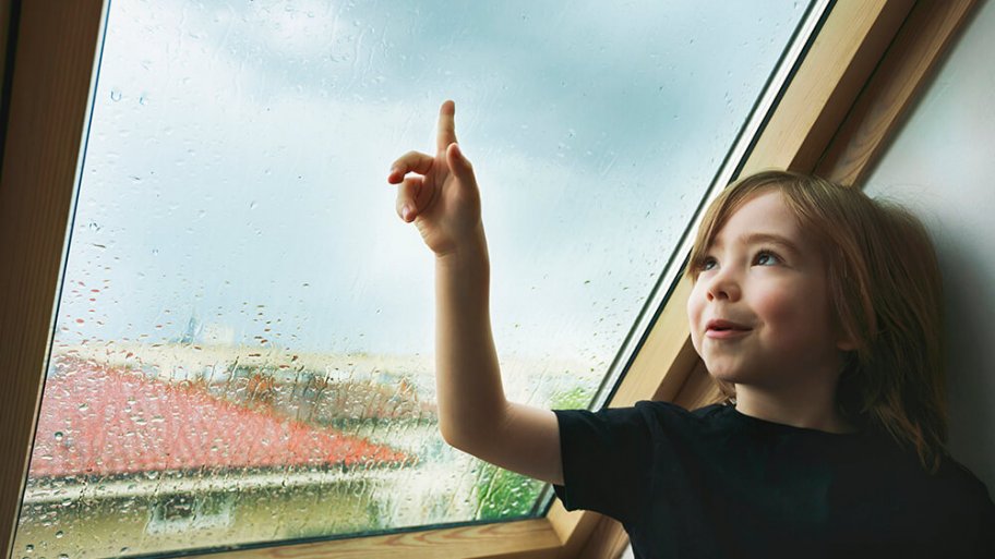 Child watching the rain from a rooftop window
