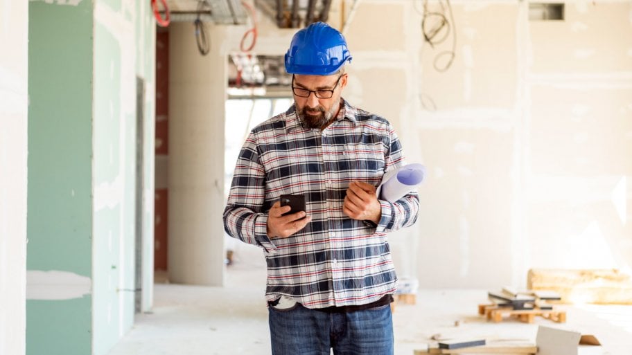 A contractor checking his phone while being on construction site