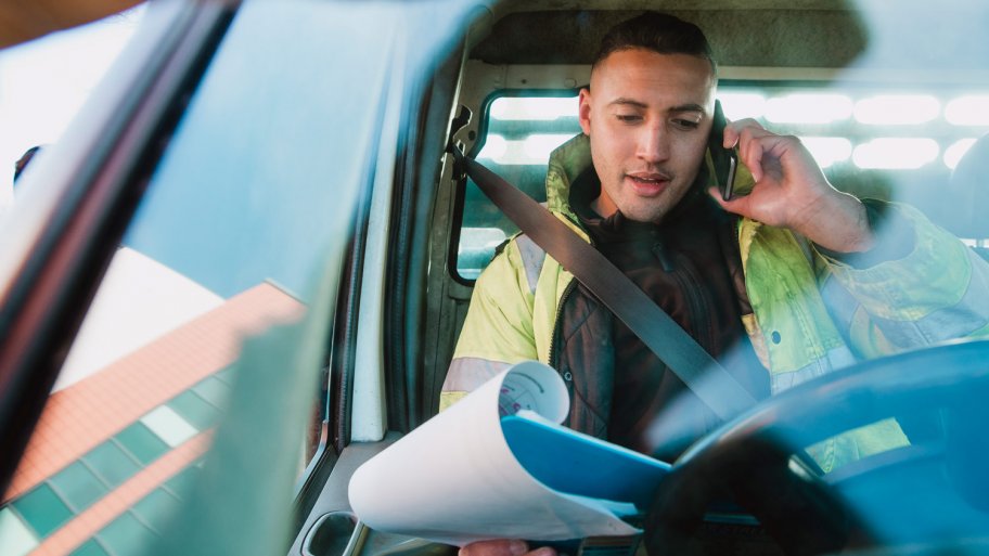 A contractor talking to his phone while sitting in his van