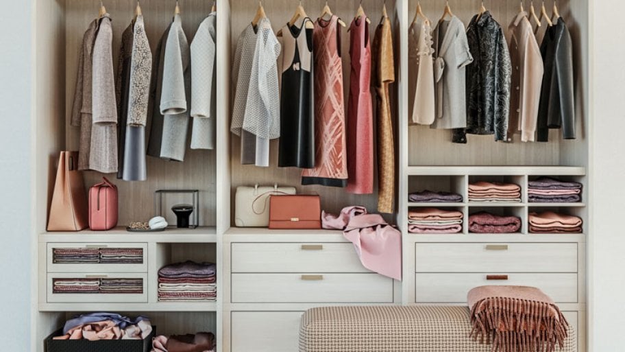 Custom closet with hanging clothes and small bench cushion