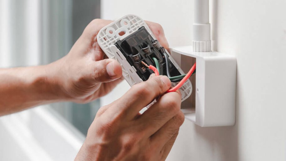 Hands working on exposed outlet wiring Hands working on exposed outlet wiring
