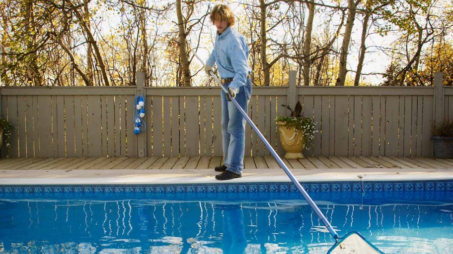 Man cleans fall leaves from pool