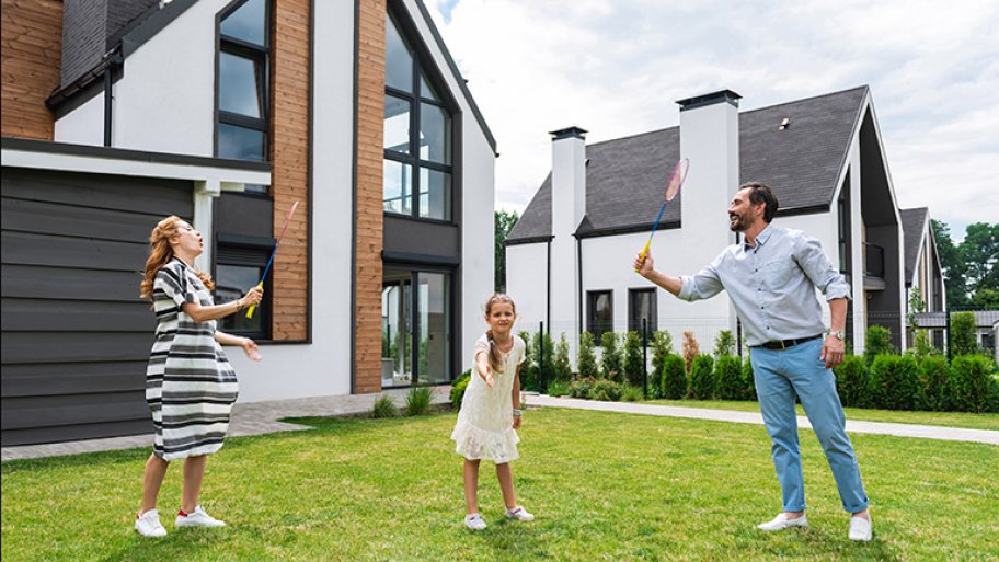 Family plays badminton in front of house