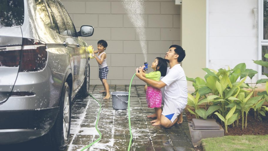 A father with his daughter and his son washing their car in the driveway (Photo by Creativa Images - stock.adobe.com)