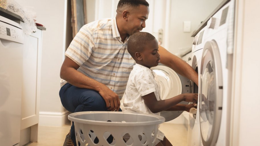 A father and his son put clothes in the dryer