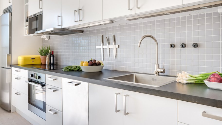 interior view of kitchen with gray countertop and white flat cabinet doors with silver handles